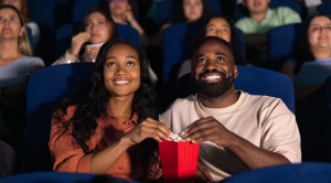 Loving couple watching a movie at the theatre and eating popcorn